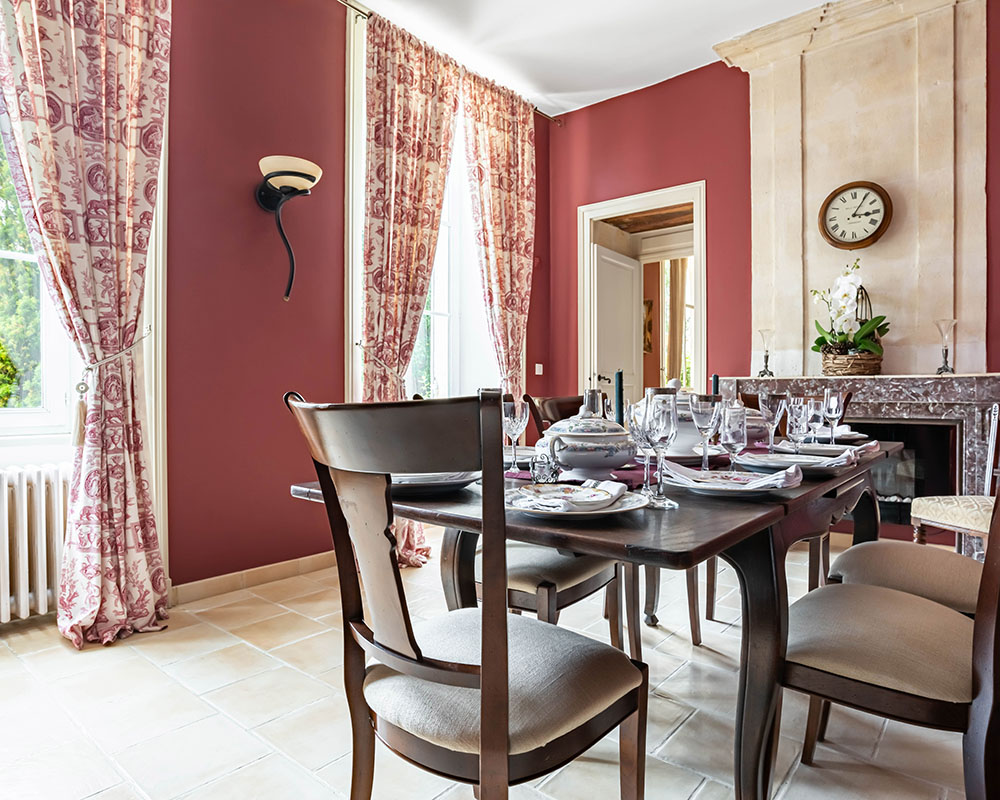 Classic french style dining room with red wall paper and oak furniture and french windows